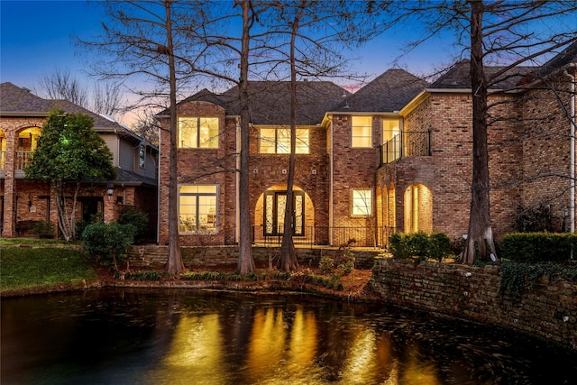 back house at dusk featuring a water view