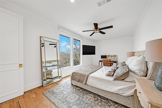 bedroom featuring ceiling fan, light wood-type flooring, and crown molding