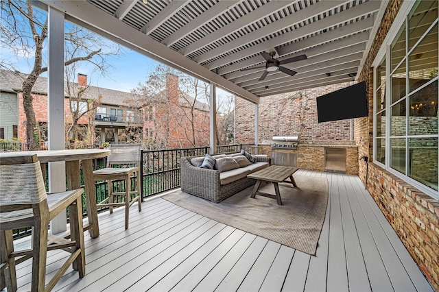 deck with an outdoor living space, ceiling fan, a grill, and exterior kitchen