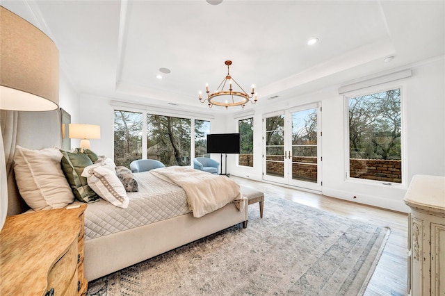 bedroom with a tray ceiling, light hardwood / wood-style floors, access to exterior, and a notable chandelier