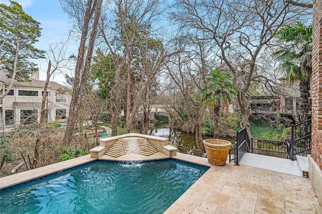 view of swimming pool featuring pool water feature, a patio, and a water view