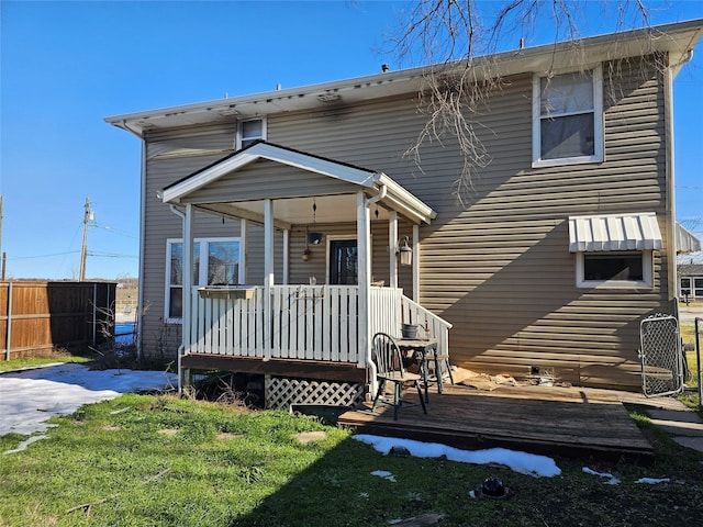 rear view of house featuring a porch and a lawn