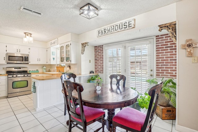 dining area featuring visible vents, a textured ceiling, and light tile patterned floors