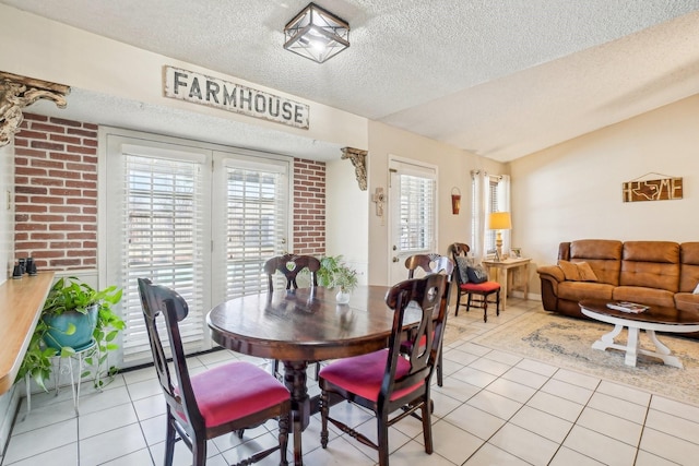 dining space featuring vaulted ceiling, brick wall, light tile patterned floors, and a textured ceiling