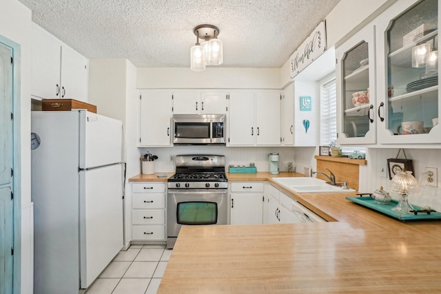 kitchen featuring light tile patterned floors, light countertops, appliances with stainless steel finishes, white cabinetry, and a sink