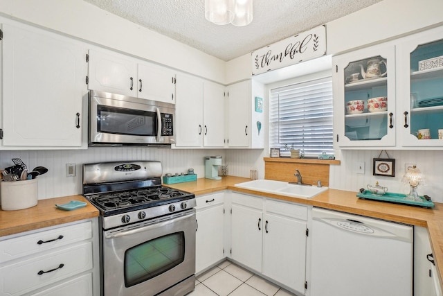 kitchen with white cabinets, stainless steel appliances, a textured ceiling, light countertops, and a sink