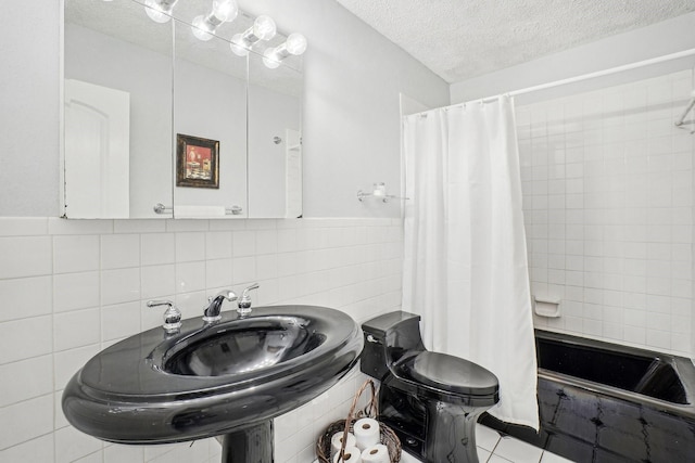 full bath with toilet, tiled shower / bath combo, tile patterned flooring, a textured ceiling, and tile walls