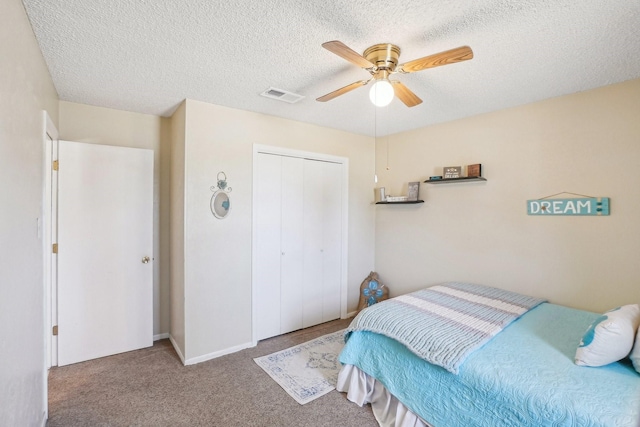 bedroom with visible vents, ceiling fan, a textured ceiling, carpet floors, and a closet