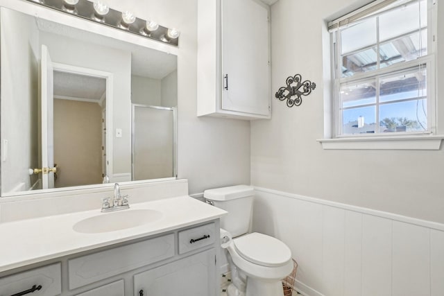 bathroom with toilet, a stall shower, vanity, and wainscoting