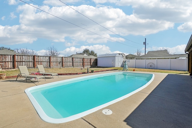 view of swimming pool with a fenced backyard, an outdoor structure, a patio, and a shed