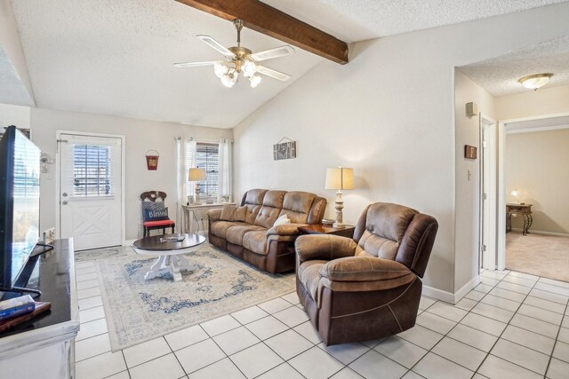 living room with baseboards, a ceiling fan, lofted ceiling with beams, a textured ceiling, and light tile patterned flooring