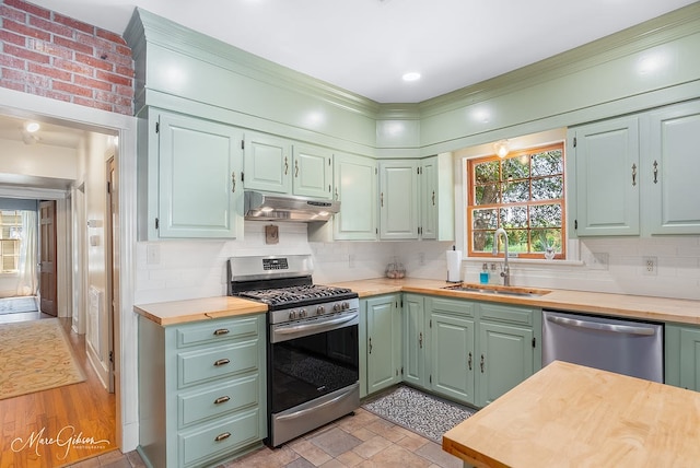 kitchen with appliances with stainless steel finishes, butcher block countertops, sink, decorative backsplash, and green cabinets