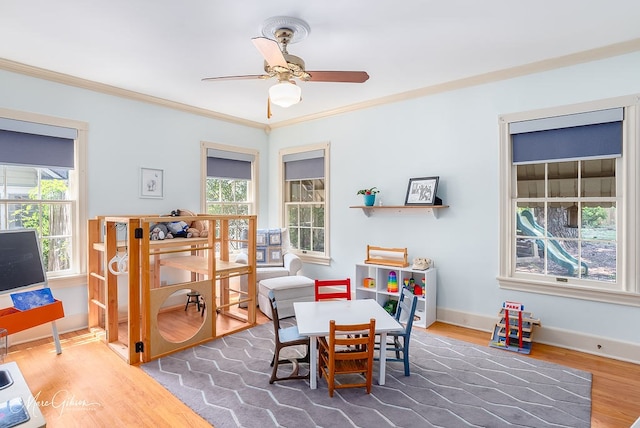 recreation room featuring wood-type flooring, ceiling fan, and crown molding