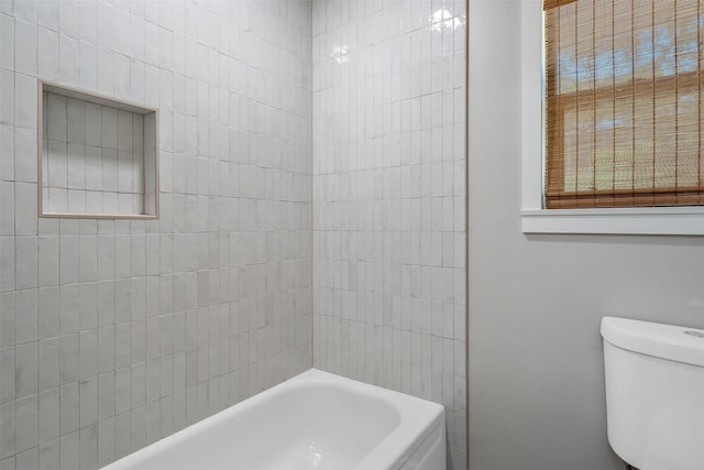 bathroom featuring tiled shower / bath and toilet