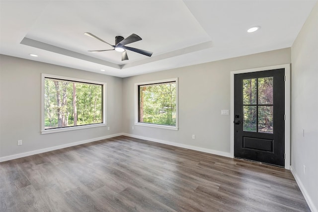 foyer entrance with dark hardwood / wood-style floors, ceiling fan, and a tray ceiling