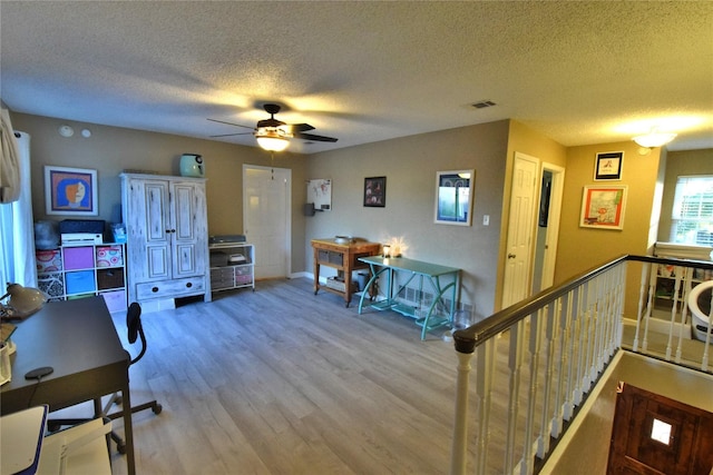 office space with ceiling fan, light hardwood / wood-style floors, and a textured ceiling