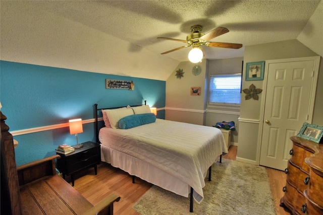 bedroom featuring ceiling fan, lofted ceiling, a textured ceiling, and light wood-type flooring