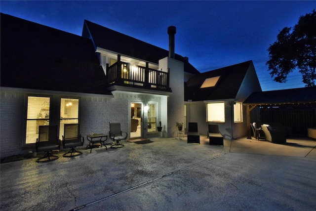 back house at twilight with a balcony and a patio area