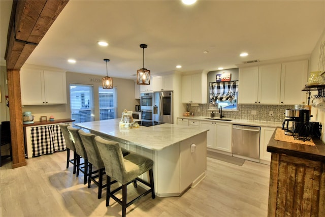 kitchen featuring stainless steel appliances, a center island, and white cabinets