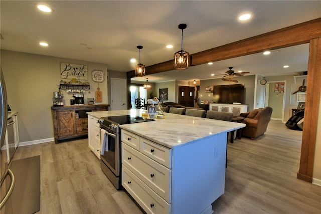 kitchen featuring white cabinetry, light stone counters, decorative light fixtures, a center island, and stainless steel electric range