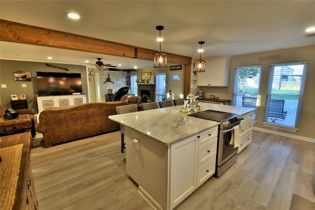 kitchen with stainless steel range with electric stovetop, a center island, pendant lighting, light stone countertops, and white cabinets