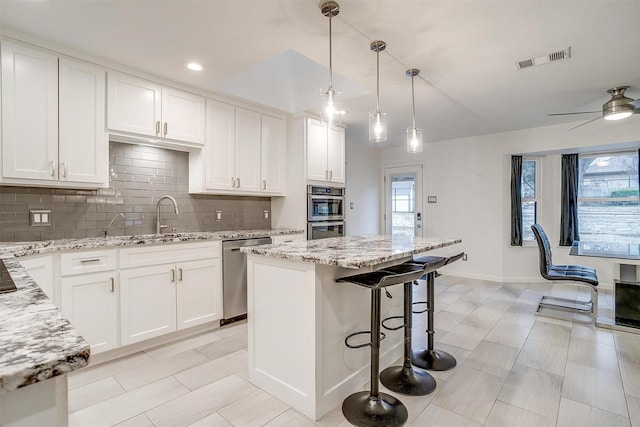 kitchen featuring a kitchen island, pendant lighting, sink, white cabinets, and stainless steel appliances