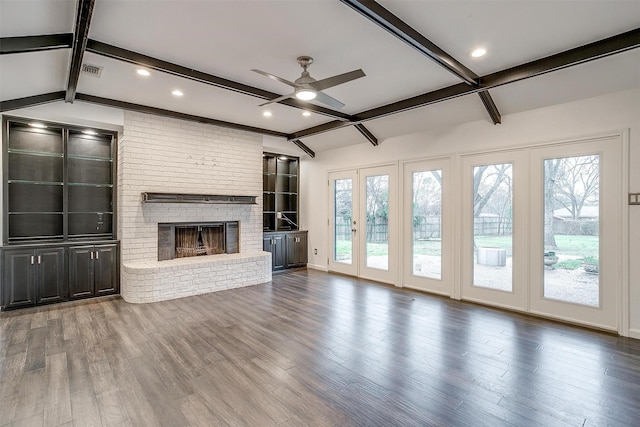 unfurnished living room with wood-type flooring, a brick fireplace, vaulted ceiling with beams, and a wealth of natural light