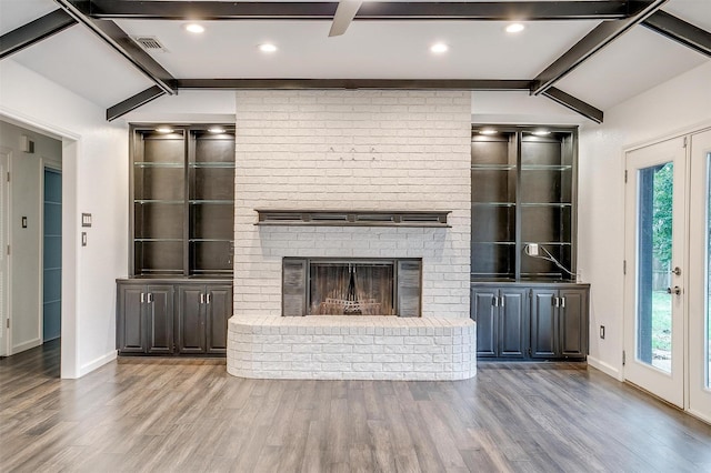 unfurnished living room with vaulted ceiling with beams, wood-type flooring, french doors, and a brick fireplace