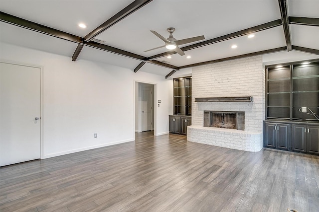 unfurnished living room with ceiling fan, a fireplace, vaulted ceiling with beams, and wood-type flooring