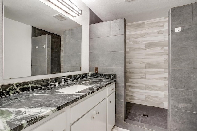 bathroom featuring vanity, a textured ceiling, and a tile shower