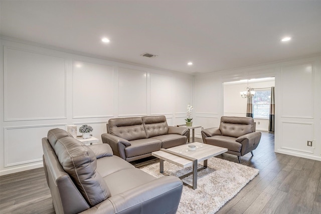 living room with crown molding, hardwood / wood-style floors, and a notable chandelier