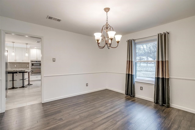 spare room featuring hardwood / wood-style flooring and an inviting chandelier