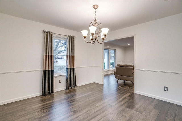 unfurnished room with dark wood-type flooring and a chandelier