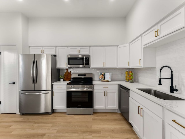 kitchen with white cabinetry, sink, stainless steel appliances, and light hardwood / wood-style floors