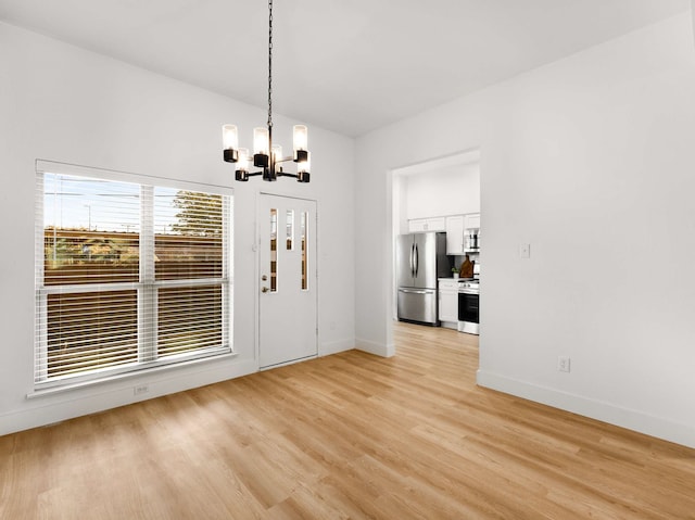 entryway featuring lofted ceiling, light hardwood / wood-style floors, and a notable chandelier