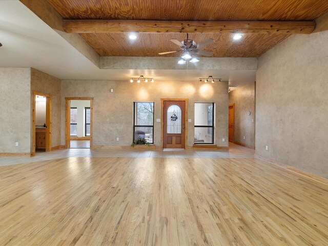 unfurnished living room featuring beamed ceiling, light wood-style floors, wooden ceiling, and a ceiling fan