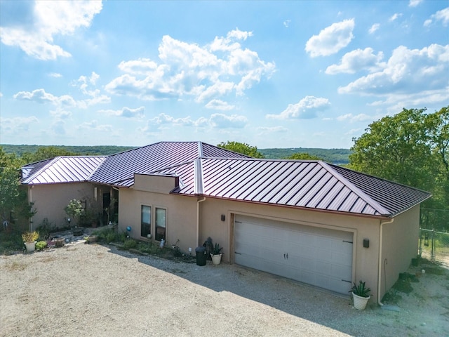 view of front of property with stucco siding, metal roof, a standing seam roof, and gravel driveway