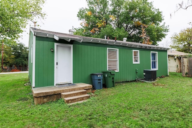 view of outbuilding with central air condition unit and a lawn