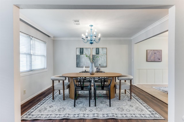 dining room featuring ornamental molding, wood-type flooring, and a notable chandelier