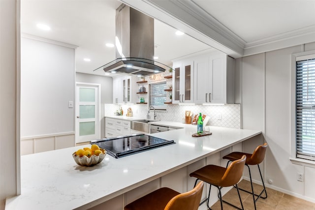 kitchen featuring island range hood, a kitchen breakfast bar, kitchen peninsula, and white cabinets