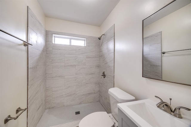 bathroom featuring vanity, a tile shower, and toilet