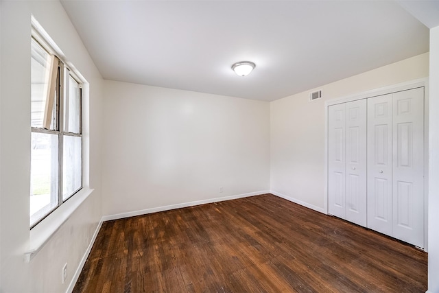 unfurnished bedroom with dark hardwood / wood-style floors and a closet