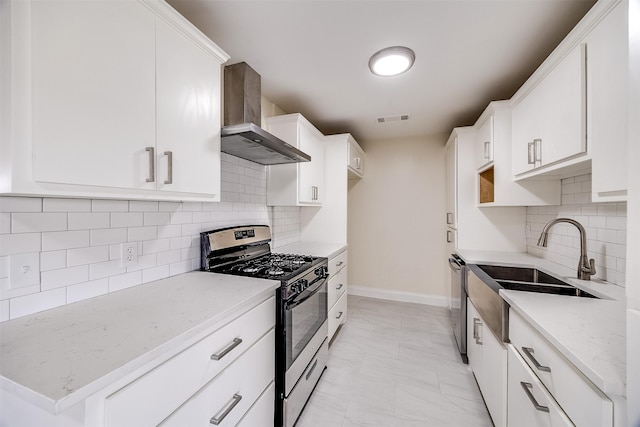 kitchen with wall chimney exhaust hood, sink, appliances with stainless steel finishes, light stone countertops, and white cabinets