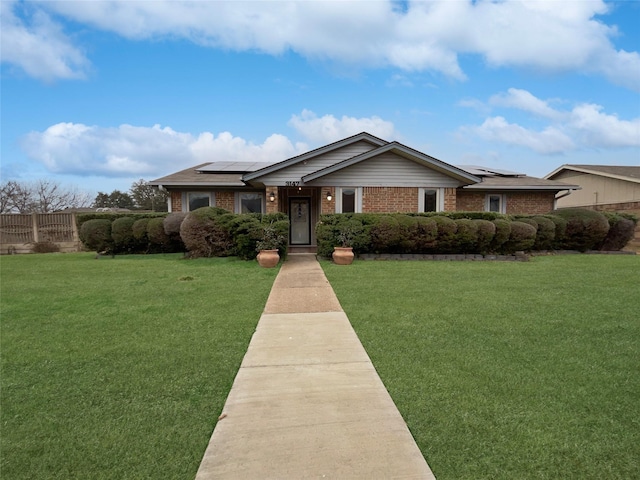 ranch-style house with a front yard and solar panels