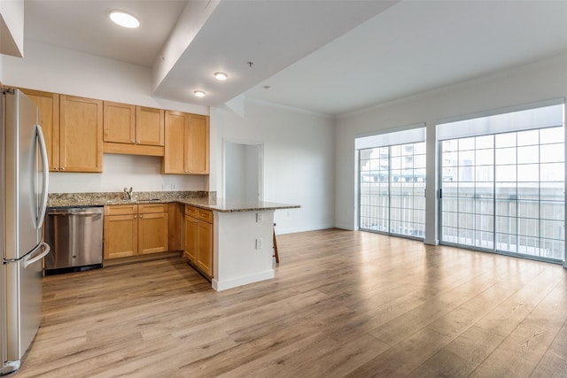 kitchen with stone countertops, a peninsula, stainless steel appliances, crown molding, and light wood-style floors