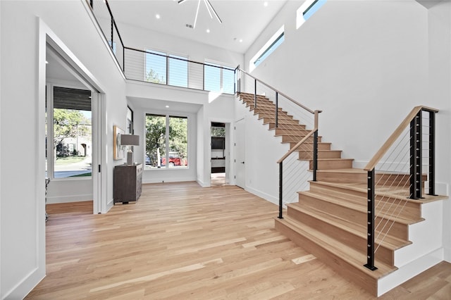 entryway featuring stairway, wood finished floors, baseboards, and a towering ceiling