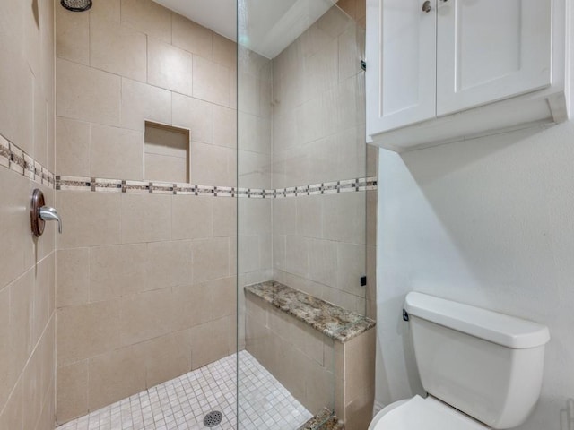 bathroom featuring a tile shower and toilet