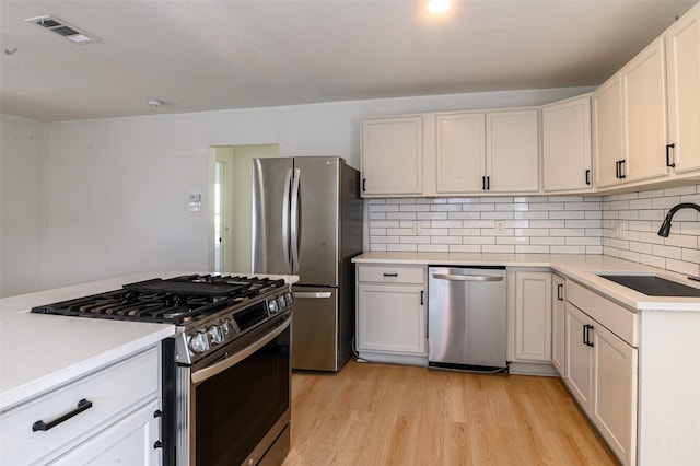 kitchen featuring visible vents, light wood finished floors, a sink, appliances with stainless steel finishes, and tasteful backsplash