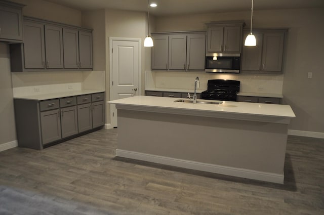 kitchen featuring gray cabinets, sink, hanging light fixtures, and a center island with sink