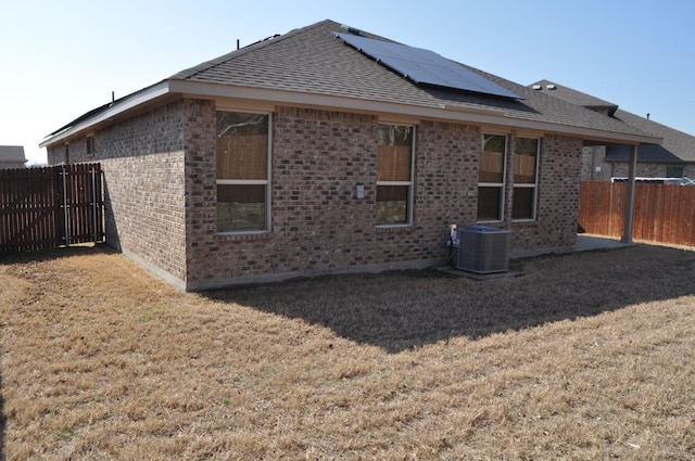 back of house featuring solar panels, a lawn, and central air condition unit